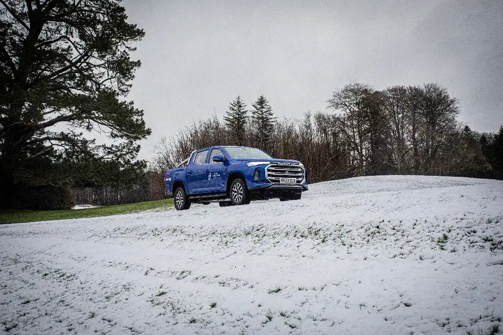 Blue pick-up truck parked on a hill in the snow