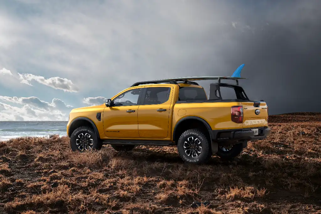 Ford Ranger Wildtrak X hero image with surfboard mounted to roof 