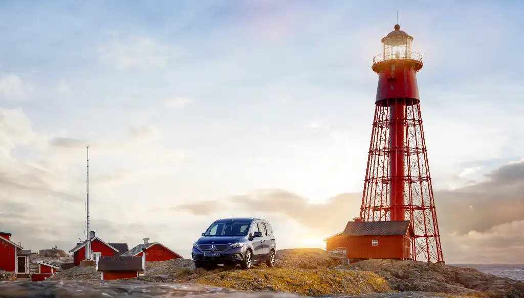 A red lighthouse on the Swedish archipelago of Hamneskar island, which is home to the famous Pater Noster lighthouse and hotel with the Mercedes-Benz EQT in front 