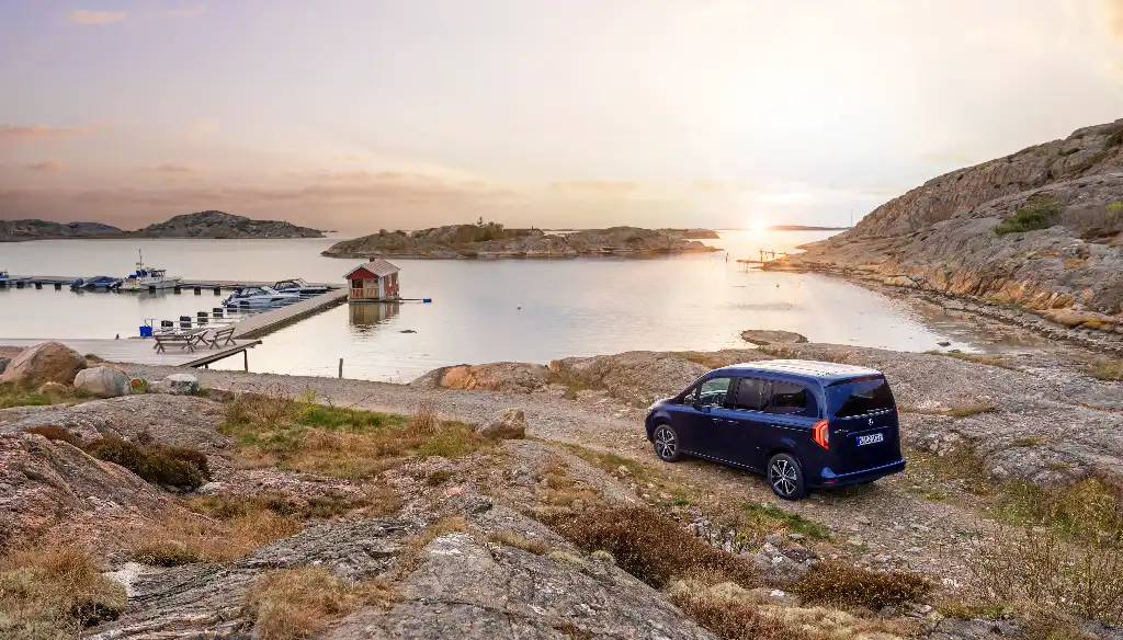 Mercedes-Benz EQT on a gravel road approaching a harbour as the sunsets