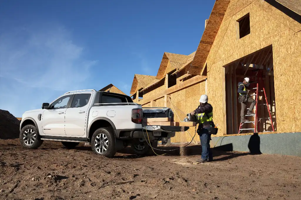 Ford Ranger Plug-in Hybrid with a man using a circular saw powered by Ford Pro OnBoard to cut wood on the rear tailgate