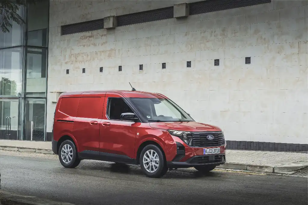 Ford Transit Courier in red, static beside a brick wall