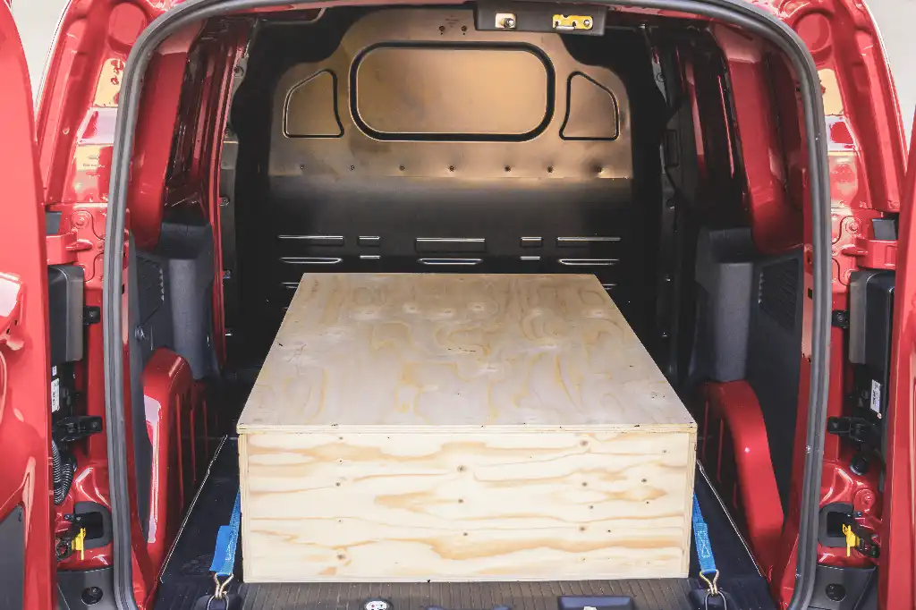 Rear view of the Transit Courier loadspace with a wooden ply box secured in the cargo area