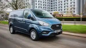 Ford Transit Custom van in blue on the road in front of a block of white flat
